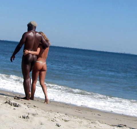 Nude interracial couple walking on beach