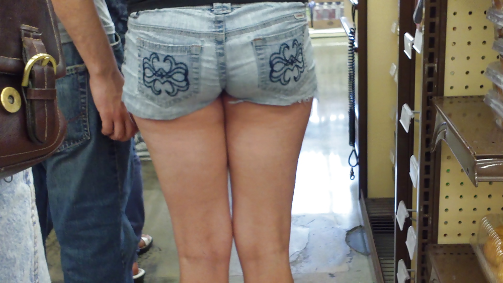 De pie en la línea detrás de la señorita de azúcar culo y el culo en pantalones cortos
 #11808513
