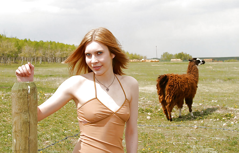 Blond teen strips infron of a fence for llamas #4624760