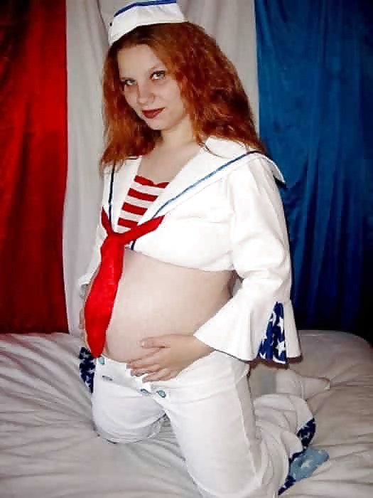 Rossa incinta che si toglie l'uniforme da marinaio
 #11952640