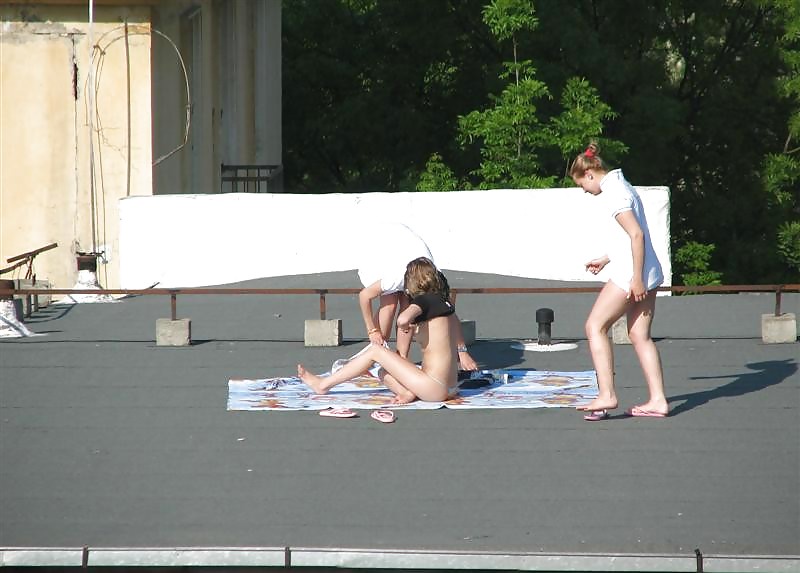 Tre ragazze vouyered che si spogliano e prendono il sole sul tetto.
 #37224183