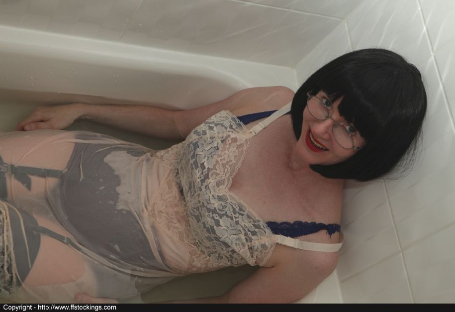Signora matura vestita in calze di nylon nere che fa un bagno
 #51757301