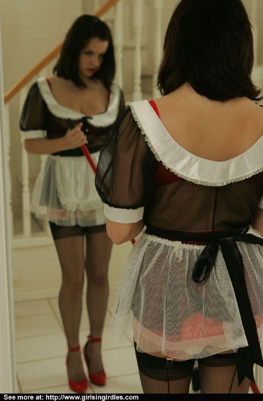 Giovane bruna in calze e uniforme da cameriera in posa davanti allo specchio
 #51291088