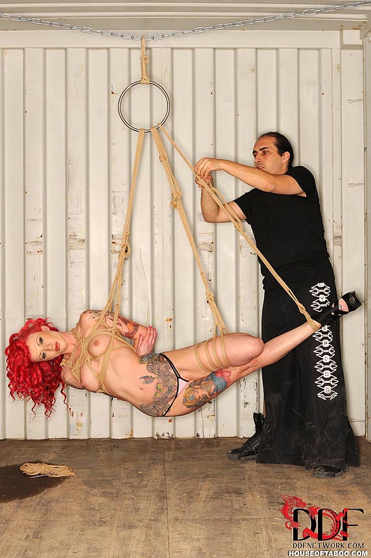 Tätowiertes rothaariges Fetisch-Modell Becky Holt hängt an einem Seil für ein BDSM-Shooting
 #52171870