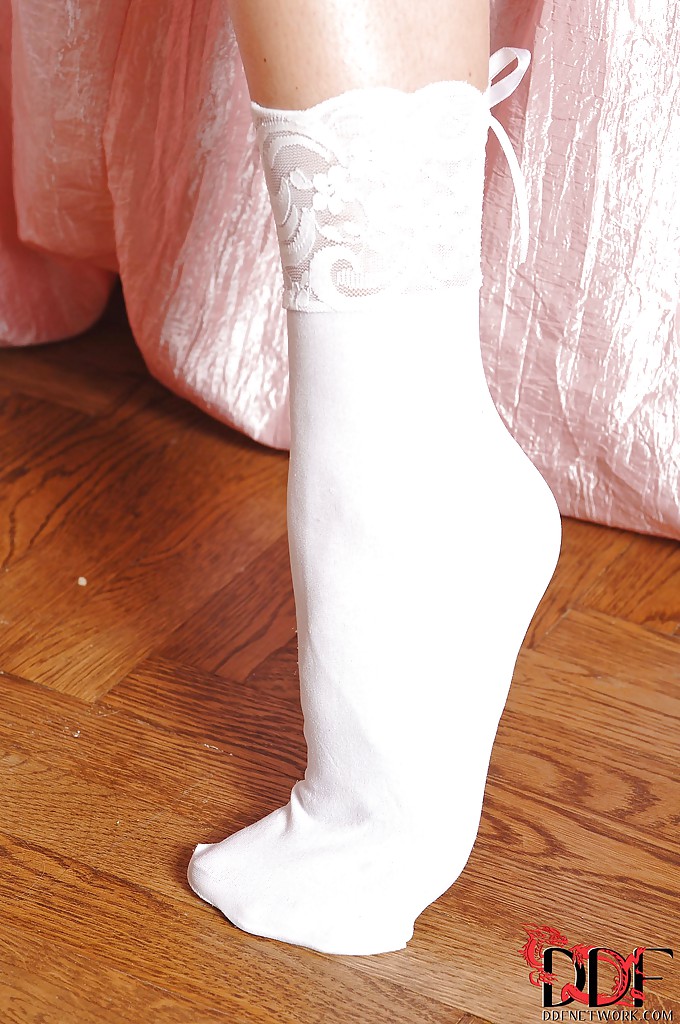 Ragazza desiderabile in lingerie e calze bianche che rivela le sue curve e i suoi piedi sexy
 #50612069