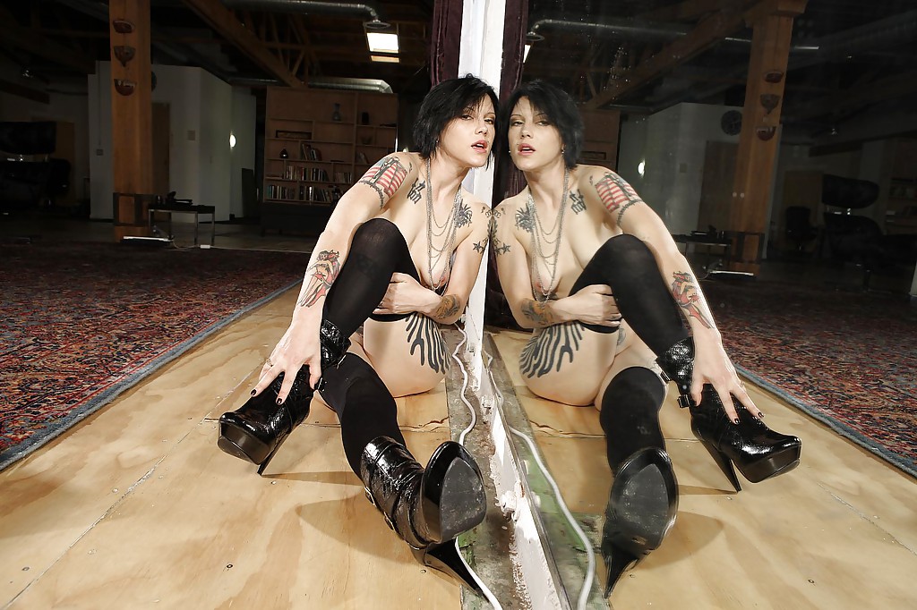 Brunette tatouée en bas noirs posant devant un grand miroir.
 #53615866