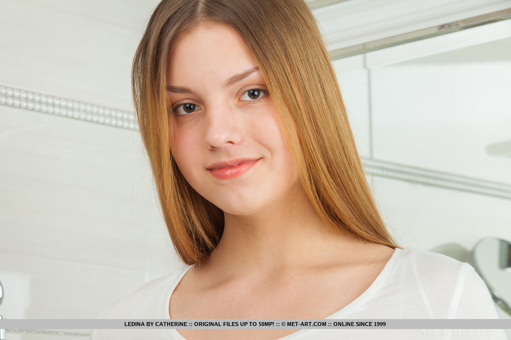 Une jeune fille rousse avec de grandes jambes de jeune étalant son vagin rasé dans une salle de bain.
 #52299626