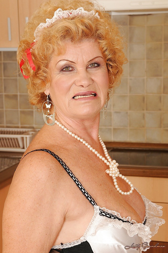Lustvolle Oma in Dienstmädchen-Uniform und Strümpfen strippt in der Küche
 #51299618