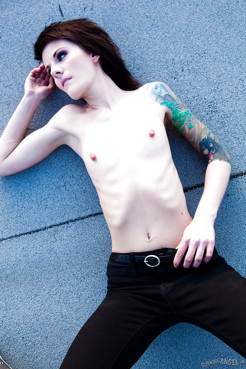 Beauté maigre au corps tatoué exposant ses petits seins en plein air sur un toit.
 #51907836