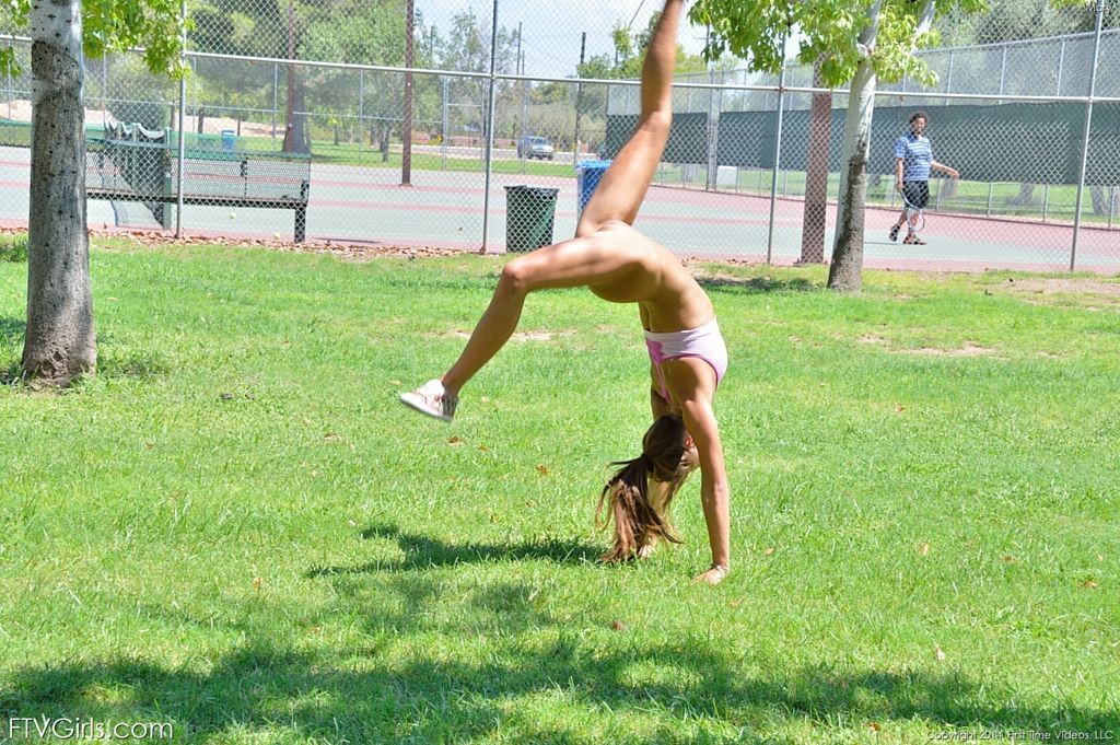 Une jolie gymnaste fait des sauts périlleux sur le court de tennis.
 #70972918