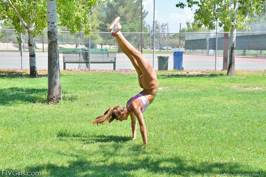 Une jolie gymnaste fait des sauts périlleux sur le court de tennis.
 #70972926