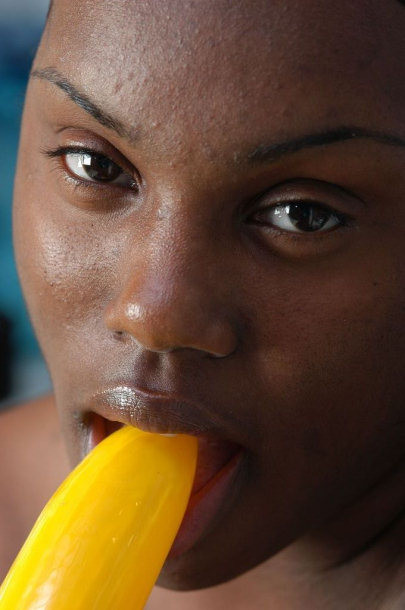 Une voisine noire nue suçant une grosse banane.
 #73442899