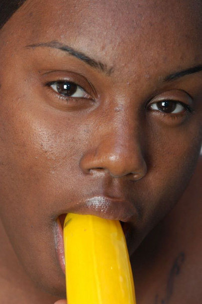Une voisine noire nue suçant une grosse banane.
 #73442902