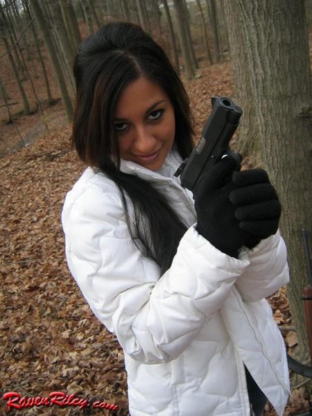 Una hermosa morena jugando con pistolas en el bosque
 #75073309