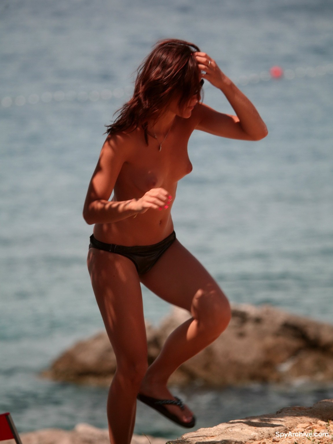 Scatti candidi di una ragazza bruna in topless sulla spiaggia
 #72242747