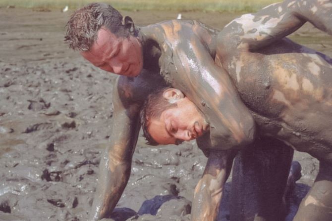 Muscle couple outdoor wrestling and thrusting the liquid mud #76947161