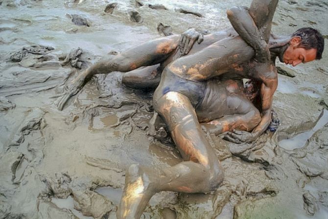 Muscle couple outdoor wrestling and thrusting the liquid mud #76947190