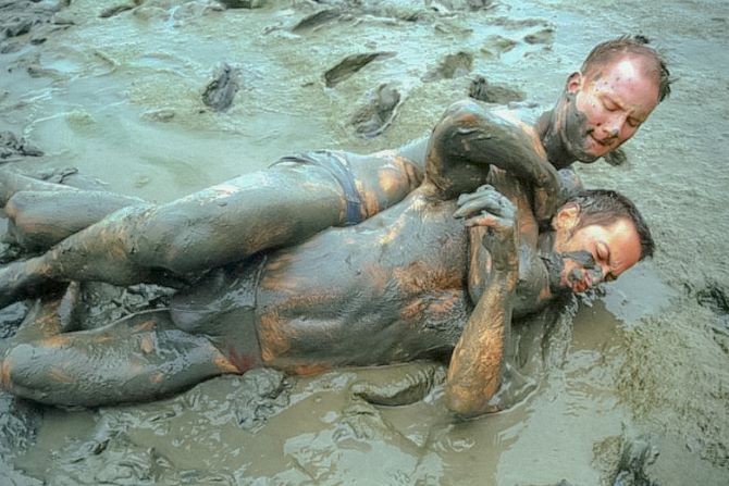 Muscle couple outdoor wrestling and thrusting the liquid mud #76947195