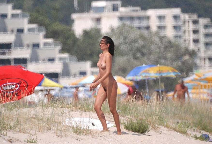 Une blonde nudiste se déshabille sur une plage publique.
 #72252452