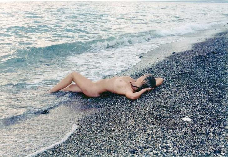 Une jeune femme sexy et bien roulée se déshabille sur une plage nudiste.
 #72255334