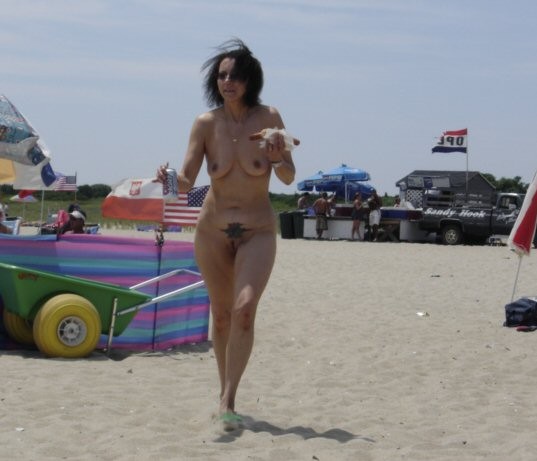 Une jeune femme sexy et bien roulée se déshabille sur une plage nudiste.
 #72255350