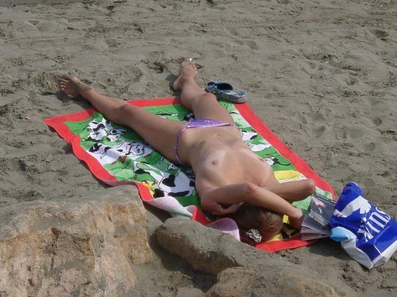 Une jeune nudiste aux cheveux noirs s'allonge au soleil.
 #72253059