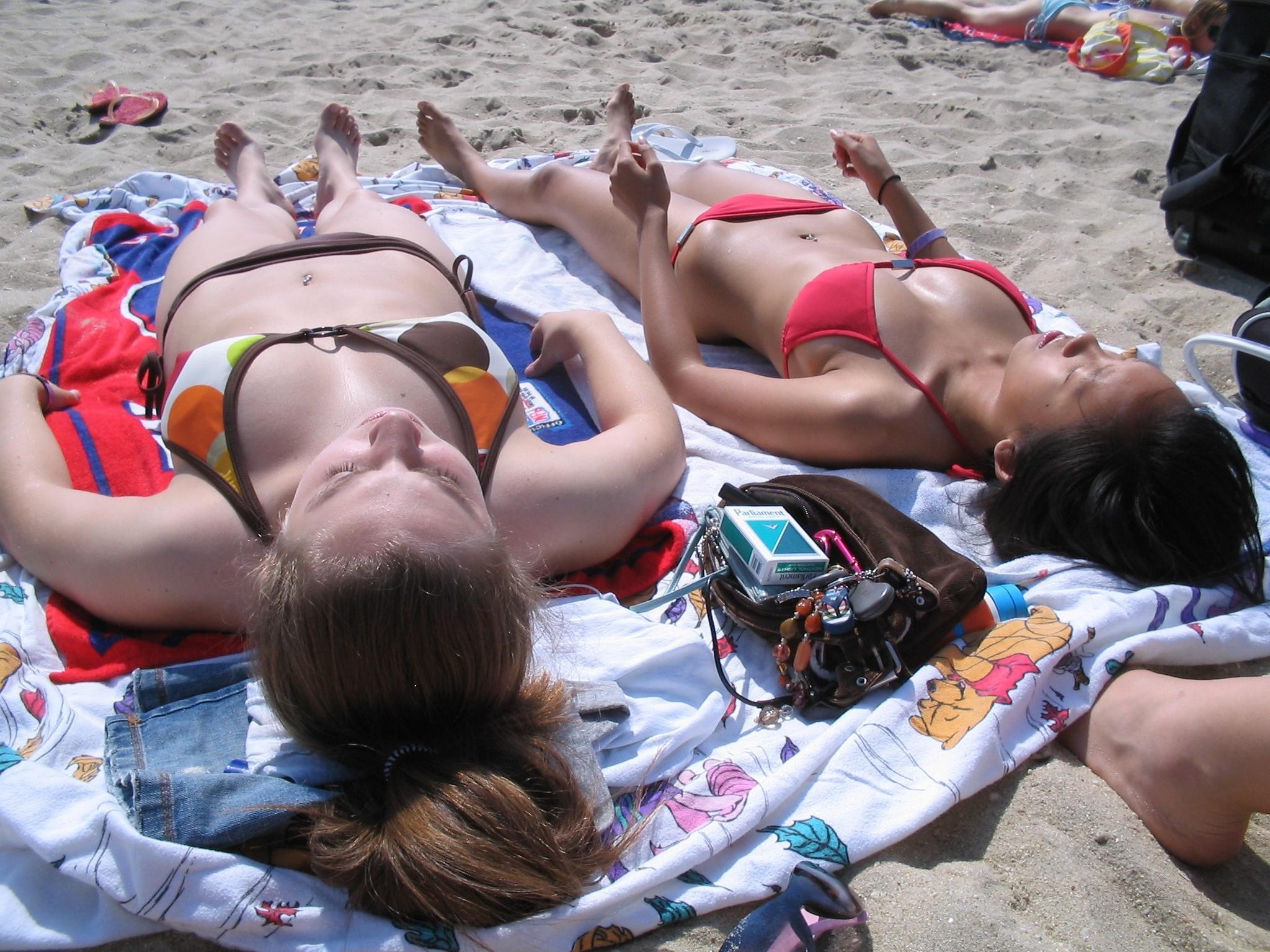 Sehr süße Mädchen liegen am öffentlichen Strand in Bikinis in der Sonne
 #72264129