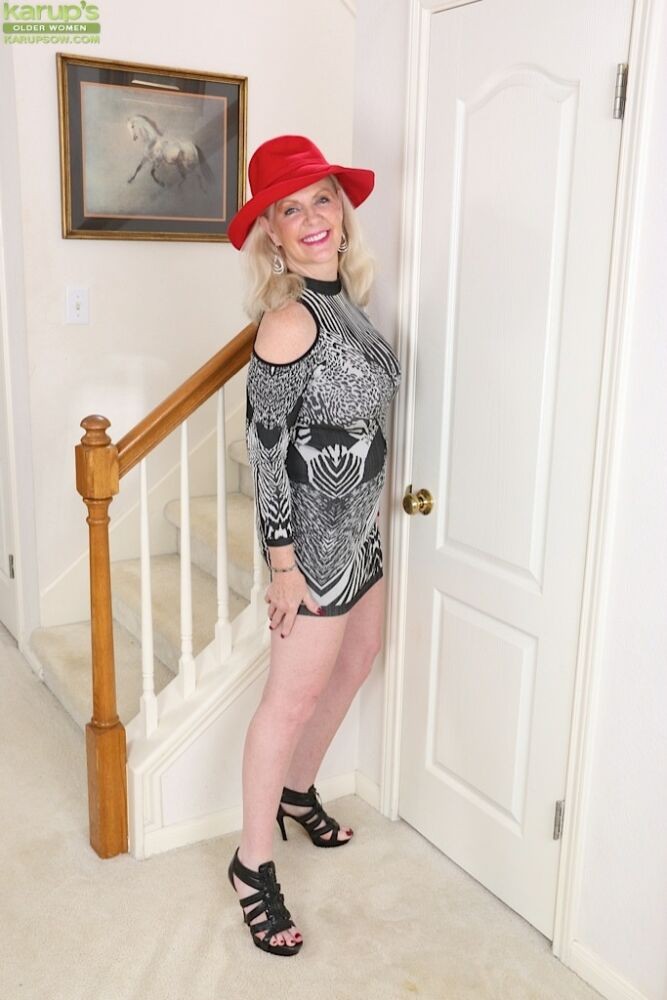 Judy Mayflower, blonde mature et plantureuse, pose avec un chapeau rouge.
 #72902238