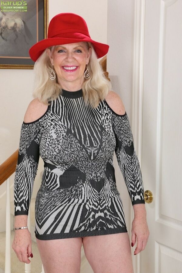 Judy Mayflower, blonde mature et plantureuse, pose avec un chapeau rouge.
 #72902245