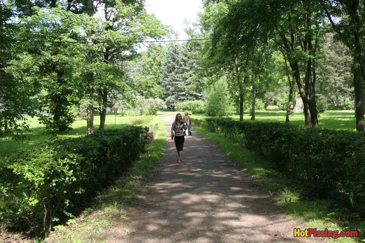 Young blondie with long hair has a piss in the middle of a park road #76521069