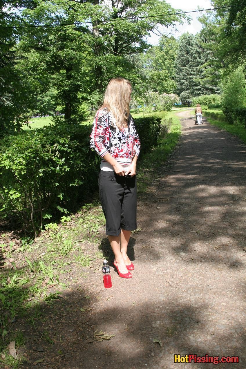 Young blondie with long hair has a piss in the middle of a park road #76521105