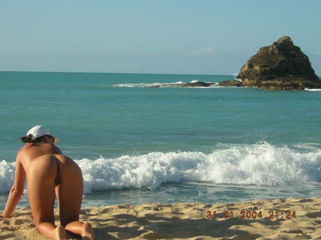 Une jeune fille aux cheveux longs se prélasse nue sur la plage.
 #72251470