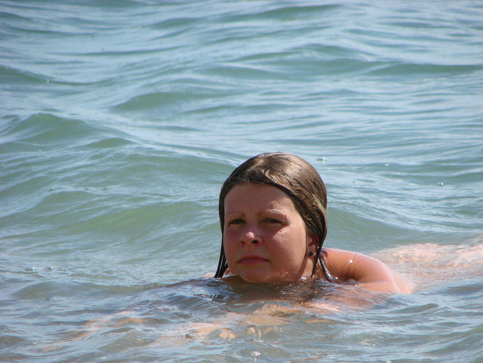 Une jeune fille aux cheveux longs se prélasse nue sur la plage.
 #72251479
