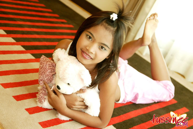 Thai teen tussinee spielt mit einem teddybär im Bett
 #67955833