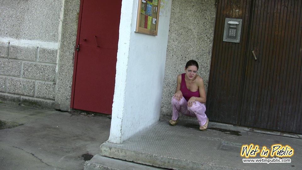 Una chica se moja en una esquina junto a la puerta de su apartamento
 #73239094