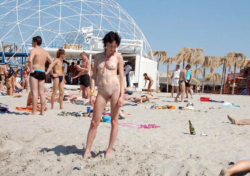 Nudista bionda si spoglia nuda in una spiaggia pubblica
 #72256774