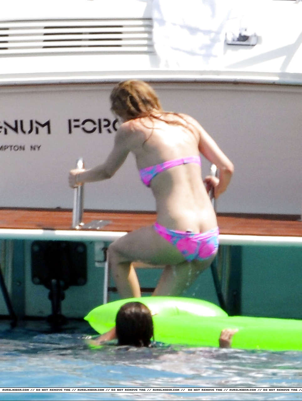 Avril Lavigne montrant une partie de son cul et son téton en bikini sur la plage.
 #75297342