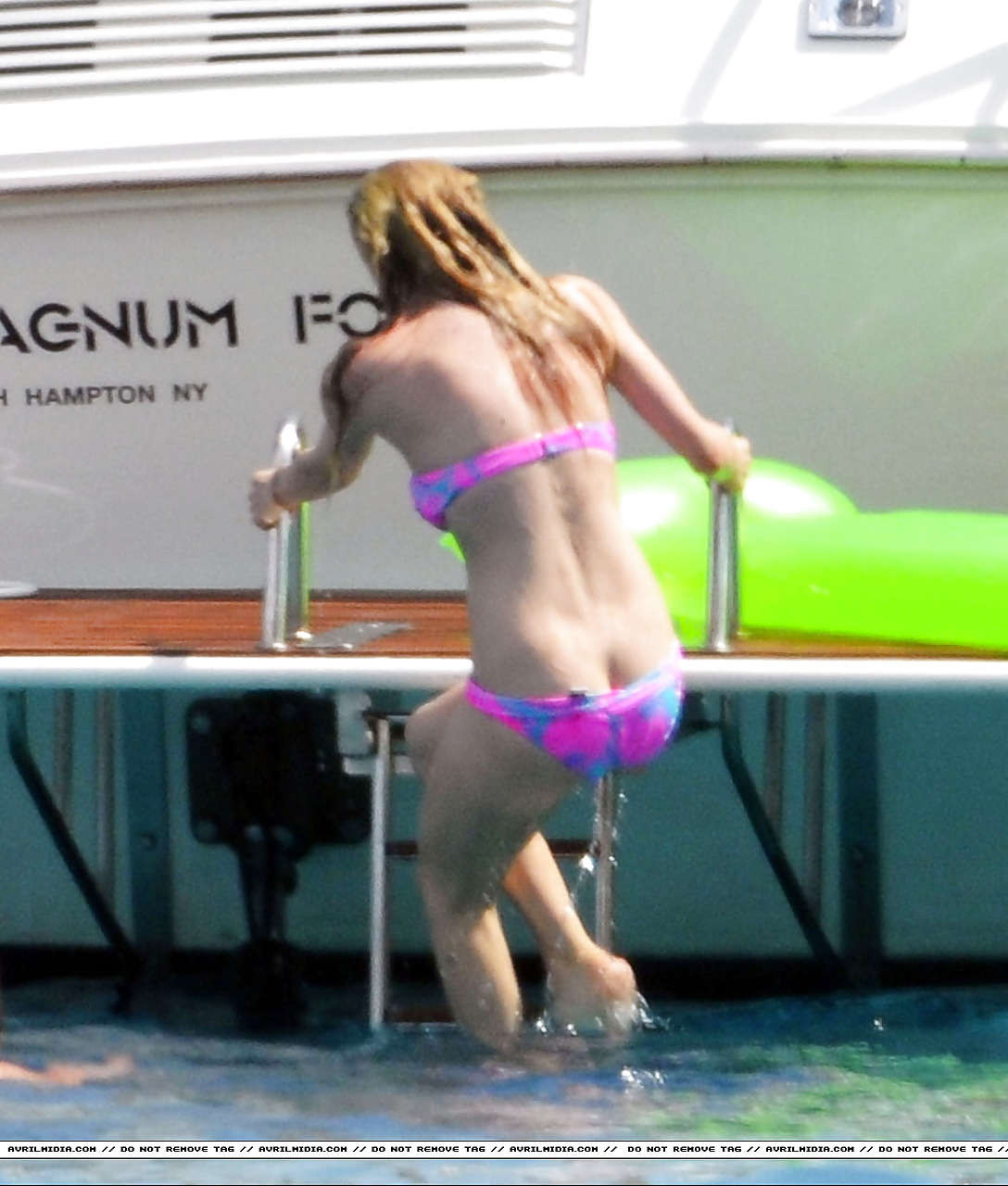 Avril Lavigne montrant une partie de son cul et son téton en bikini sur la plage.
 #75297361
