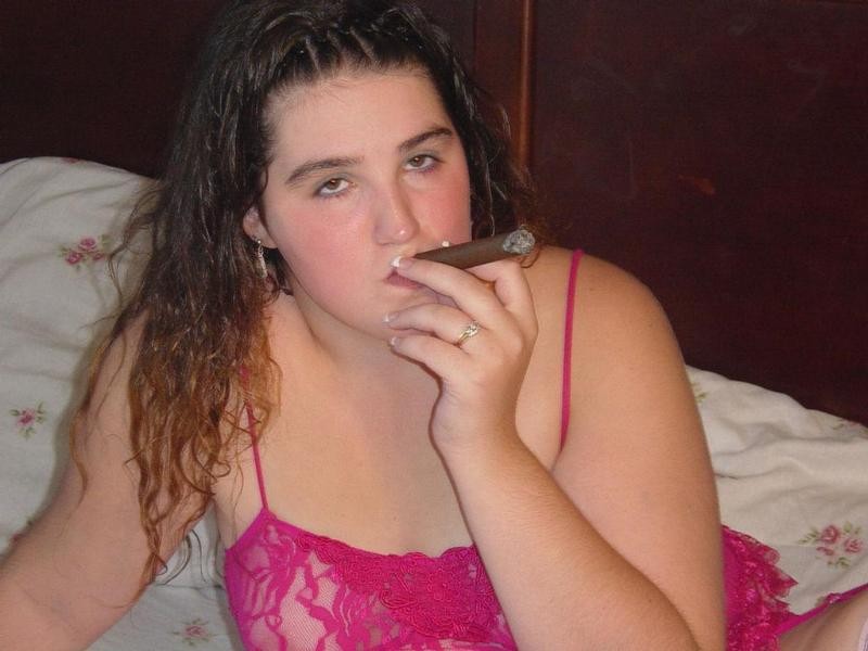 Nena regordeta fumando casualmente un gran cigarro en la cama
 #79055604