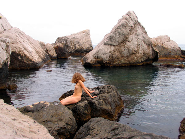 Une jeune femme à la poitrine généreuse exhibe son corps nu sur la plage.
 #72253176
