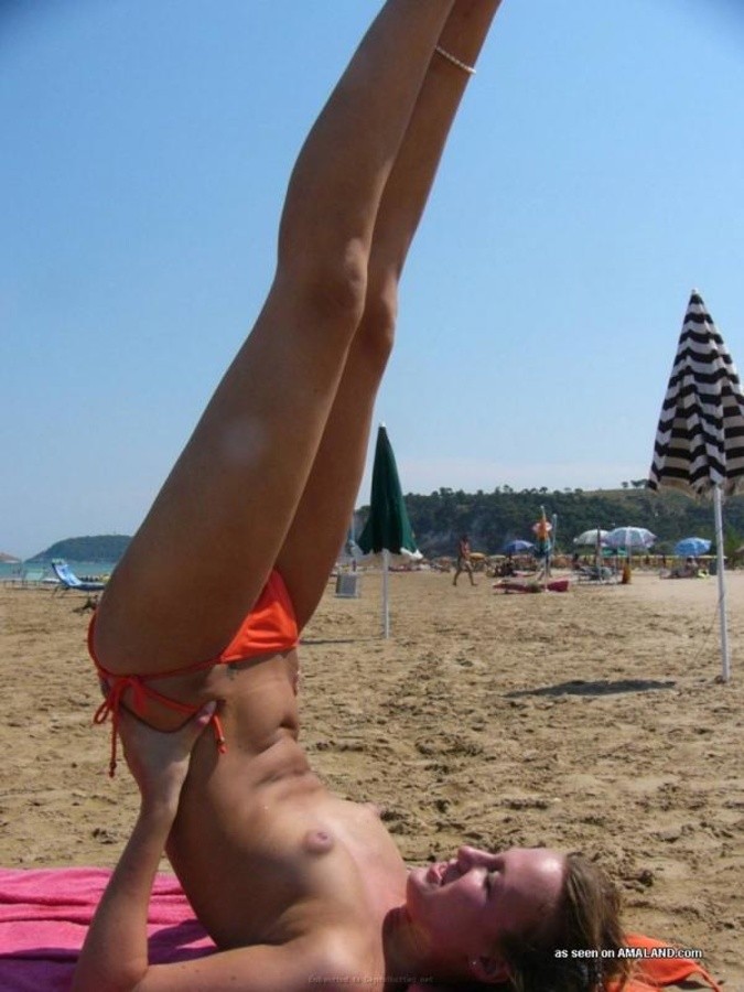 Une jeune blonde s'amusant les seins nus à la plage.
 #67627350
