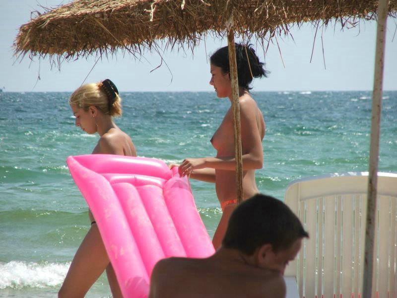 Jeunes nus jouant ensemble sur une plage publique
 #70251115