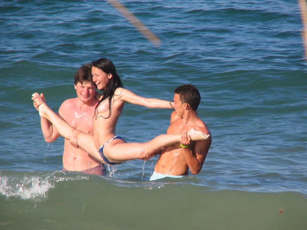 Amici giovani nudi giocano in una spiaggia pubblica
 #72250362