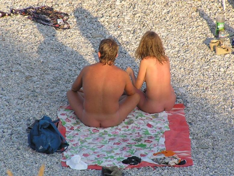 Amici giovani nudi giocano in una spiaggia pubblica
 #72250408