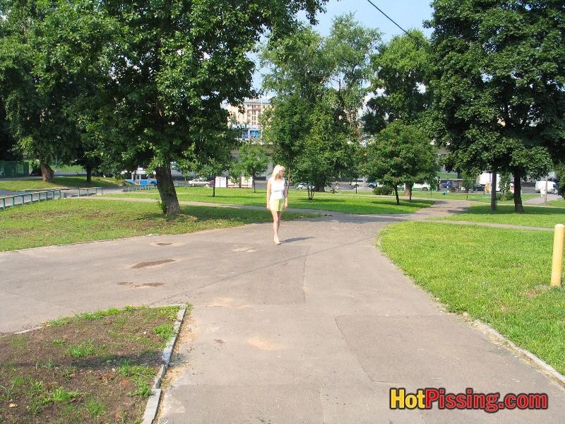 Une bimbo aux gros seins se tient debout pour voir sa chatte qui pisse sur un banc public.
 #76521481