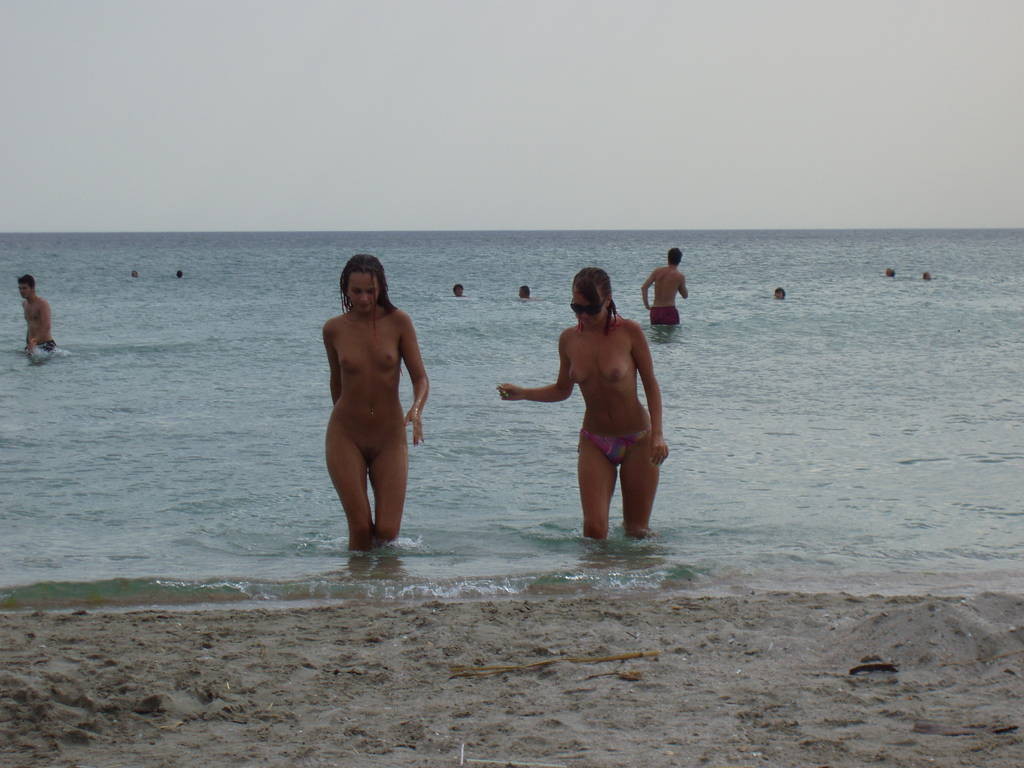 Un paio di amici giovani nudisti fanno vapore sulla spiaggia
 #72248089