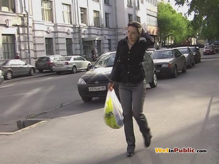 Perplexed brune walks in the street in pee-drenched tight gray pants #78595165