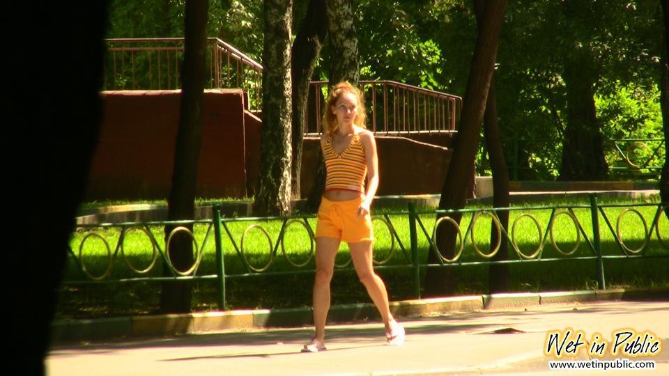Unbequeme orangefarbene Shorts eines schlanken Mädchens, das zu stark pinkeln musste
 #73244559