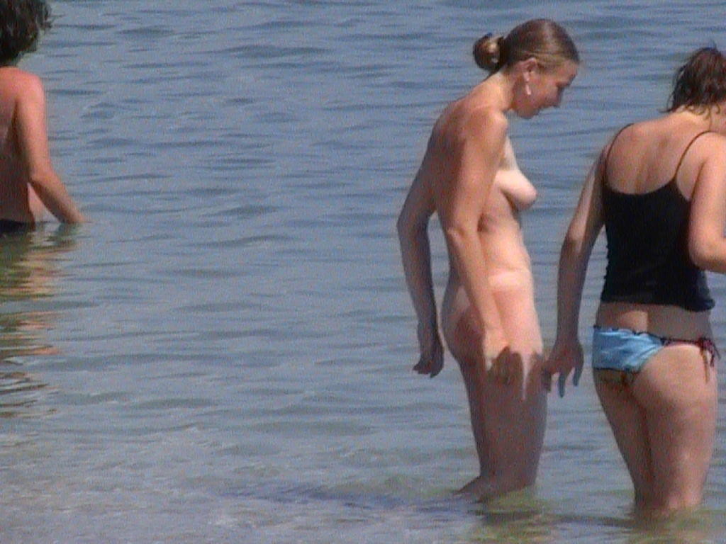 Joven con curvas lo desnuda todo en una playa nudista bajo el sol
 #72255658