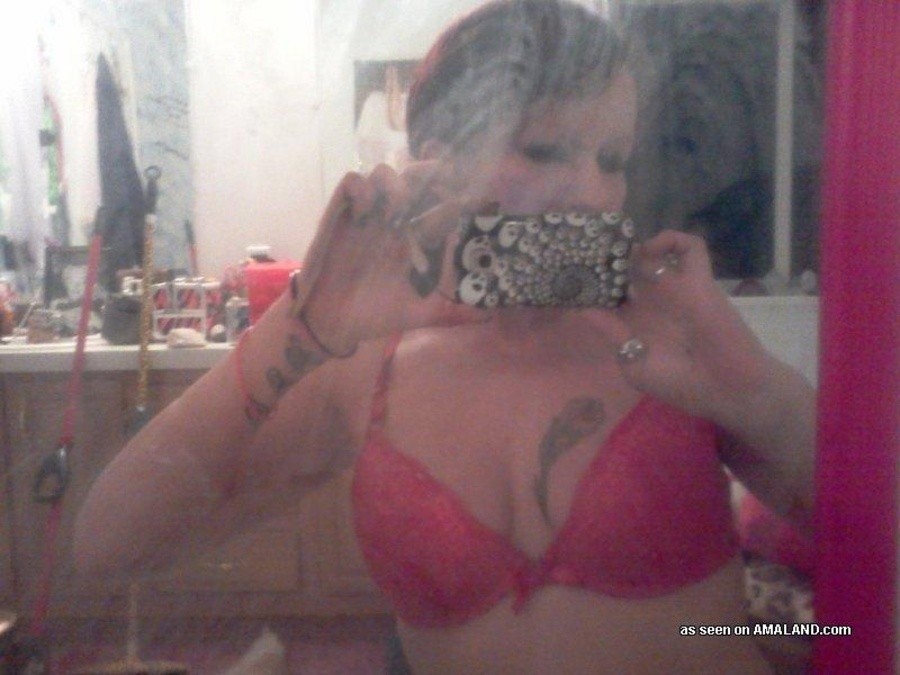 Une nana tatouée s'auto-fixe devant le miroir.
 #67643551